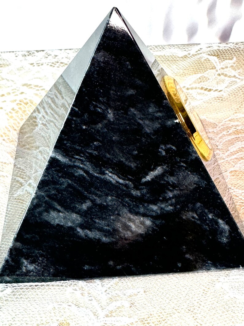 May include: A black marble pyramid with a gold-colored clock face on one side.