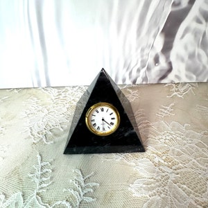 May include: Black marble pyramid clock with gold-tone hands and Roman numeral markings on the clock face.