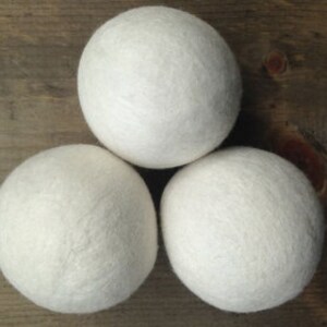 May include: Three white wool dryer balls. These balls are used in the dryer to help reduce drying time and soften clothes.