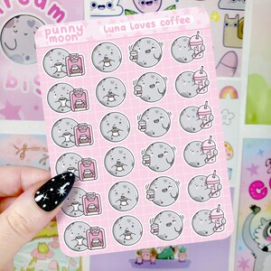 Op de afbeelding: Een vel roze stickers met een cartoon maan die een kopje koffie en een koffiezetapparaat vasthoudt. De stickers zijn in een rasterpatroon gerangschikt en bovenaan staat "Luna Loves Coffee".