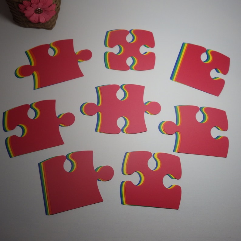 K&ouml;nnte beinhalten: Acht rote Puzzle-Teile mit Regenbogenstreifen. Die Teile sind in einem Kreis auf wei&szlig;em Hintergrund angeordnet.