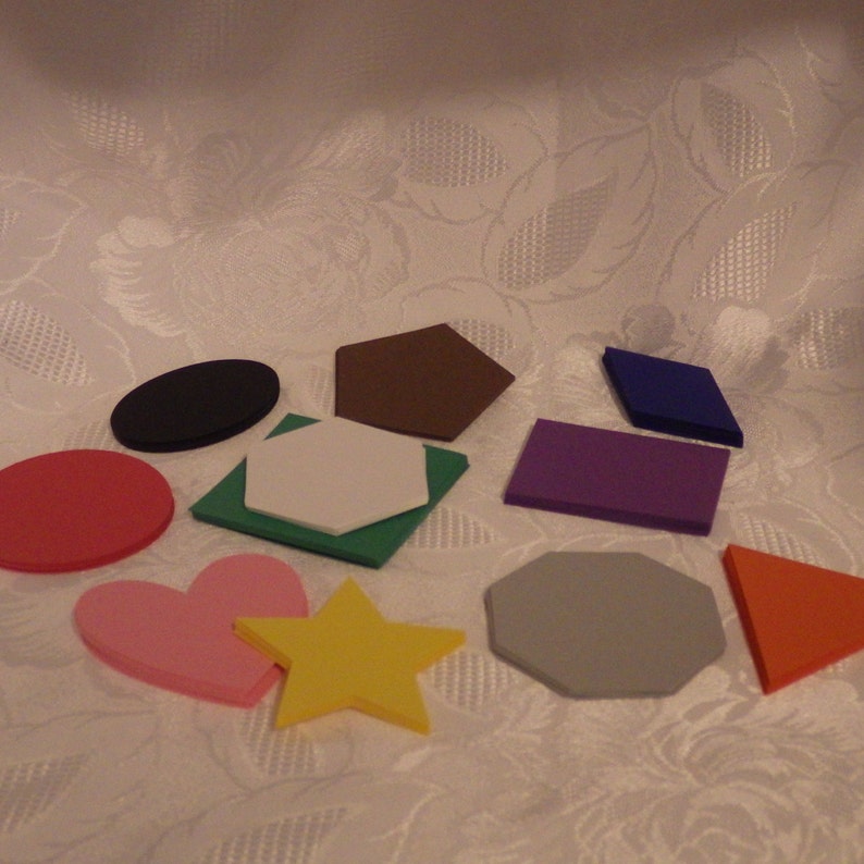 May include: A set of ten colourful felt shapes, including a circle, heart, star, square, pentagon, hexagon, octagon, and triangle. The shapes are all different sizes and are arranged on a white background.