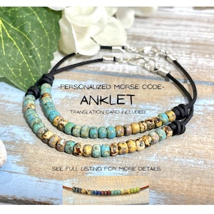 May include: A personalised Morse code anklet with turquoise and yellow beads on a black leather cord. A translation card is included.  "Personalized Morse Code - Anklet - Translation Card Included" is printed on the image.