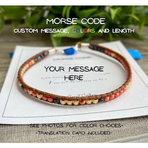 May include: A brown leather bracelet with multi-colored beads, including orange, yellow, and blue. The bracelet is on a white card with the text "MORSE CODE CUSTOM MESSAGE, COLORS AND LENGTH YOUR MESSAGE HERE -SEE PHOTOS FOR COLOR CHOICES- -TRANSLATION CARD INCLUDED-"