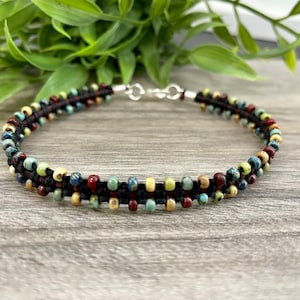 May include: A black beaded bracelet with a silver clasp. The beads are multi-colored and include red, green, blue, and yellow.