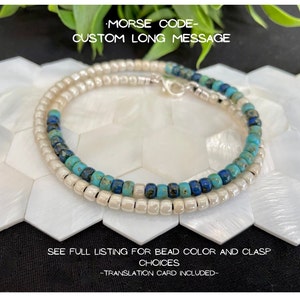 May include: A white and turquoise beaded bracelet with a silver clasp. The bracelet is on a white background with a hexagonal pattern. The text "MORSE CODE- CUSTOM LONG MESSAGE" is at the top of the image. The text "SEE FULL LISTING FOR BEAD COLOR AND CLASP CHOICES" is in the middle of the image. The text "-TRANSLATION CARD INCLUDED- " is at the bottom of the image.