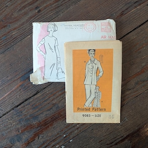 May include: Vintage sewing pattern with a woman's fashion illustration on an orange background. The pattern is labeled "9083-SIZE 44." An envelope with a fashion sketch and the text "AIR MAIL" is also visible. The background is a wooden surface.