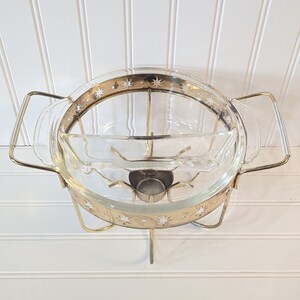 May include: A gold metal serving stand with a glass bowl and a smaller glass dish. The bowl and dish have a gold rim with a white star pattern.