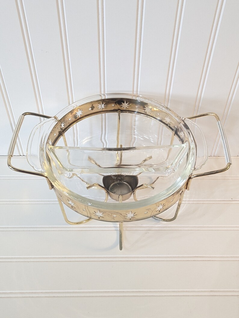 May include: A gold metal serving stand with a glass bowl and a smaller glass dish. The bowl and dish have a gold rim with a white star pattern.