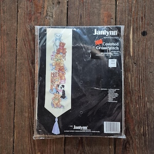 Op de afbeelding: Een verzegelde Janlynn kruissteekkit met een ontwerp van teddyberen. Het ontwerp is verticaal gerangschikt. De verpakking is voorzien van de tekst "Counted Cross Stitch" en "BEARS BELL PULL".
