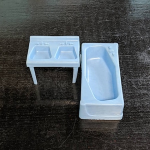 以下が含まれることがあります： 青いプラスチック製のドールハウス用バスルームセット。ダブルシンクとバスタブ付きです。