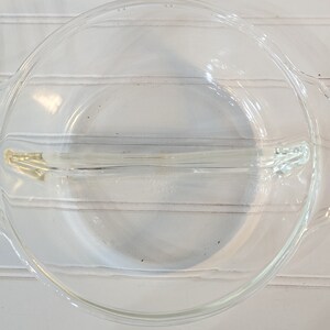 May include: A clear glass pie plate with a divider in the middle. The plate is designed for making two different pies or desserts.