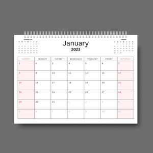 May include: A white calendar with a black spiral binding. The calendar is for January 2023 and has the days of the week labeled at the top. The numbers for each day are in red.