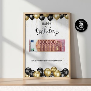 Puede incluir: Impresión enmarcada con temática de cumpleaños. La impresión presenta las palabras "Happy Birthday", un gráfico de un billete de 1.000.000 de euros y globos. También se incluye el texto "Have fun with your first million".