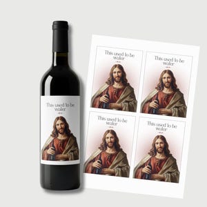 Puede incluir: Una botella de vino oscuro con una etiqueta que presenta a Jesús sosteniendo una botella, con el texto "This used to be water." Junto a ella, cuatro pegatinas con la misma imagen y texto.