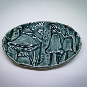 May include: A white ceramic mug with a black handle and the text "But First, Coffee" in a bold, black font. The mug is set against a plain white background, highlighting its simple design.