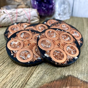 Peut inclure: Six sous-verres en r&eacute;sine noire avec du fil de cuivre et des paillettes blanches incrust&eacute;s dans la r&eacute;sine. Chaque sous-verre pr&eacute;sente un motif circulaire avec une spirale de fil de cuivre au centre.