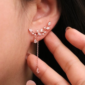 May include: Rose gold ear cuff with a delicate chain and sparkling clear stones in a leaf design.