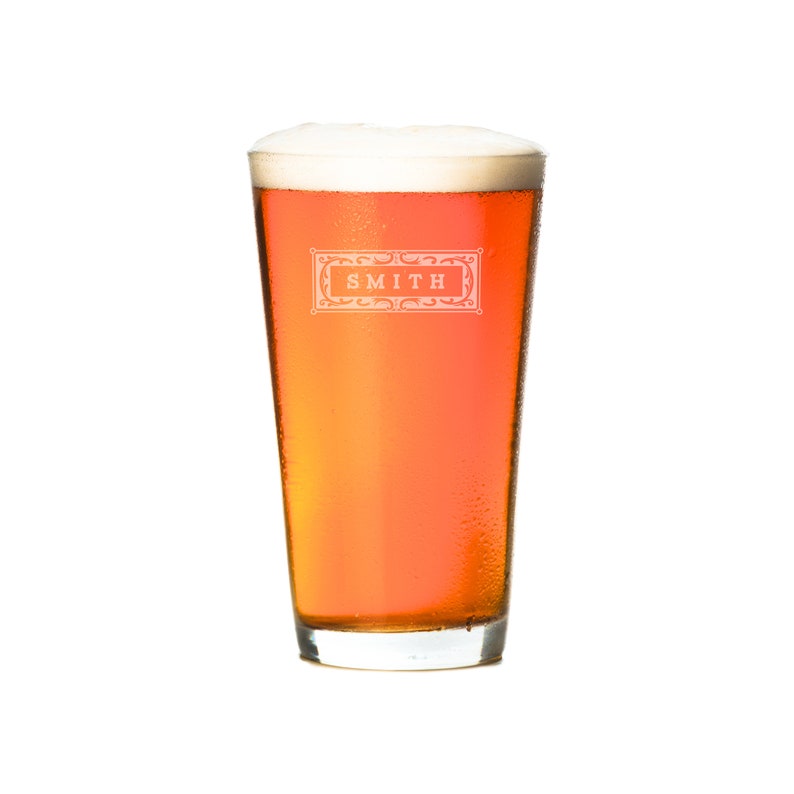 Puede incluir: Un vaso alto de cerveza de color &aacute;mbar con una cabeza blanca. El vaso tiene un logotipo que dice "SMITH" en un marco decorativo.