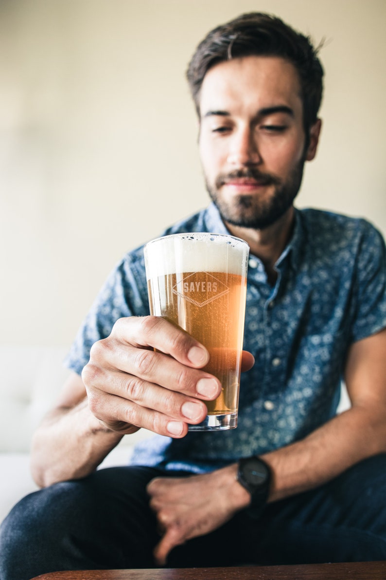 Puede incluir: Una persona sosteniendo un vaso de cerveza con la palabra "Sayers" grabada en el lateral. La cerveza es de color claro y tiene una cabeza blanca.