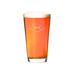 Puede incluir: Un vaso alto de cerveza &aacute;mbar con una cabeza blanca. El vaso tiene un logotipo que dice "SMITH" en forma de diamante.