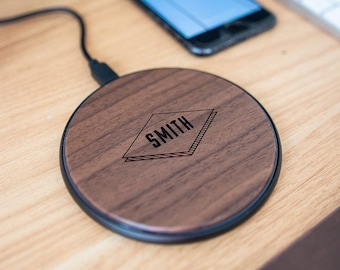 May include: A round, wooden wireless charging pad with a black rim. The pad has a dark wood grain and the word "SMITH" is engraved in a diamond shape in the center.