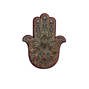 以下が含まれることがあります： 中央に青い目をつけた、金色とワインレッドのハmsaの手。ハmsaは、保護と幸運の象徴です。