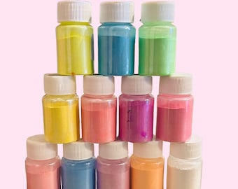 May include: A set of 10 small bottles filled with colorful iridescent powder. The bottles are arranged in a pyramid shape, with the yellow bottle at the top.