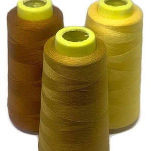May include: Three spools of thread in different shades of yellow and brown. The spools are made of plastic and have a yellow top.