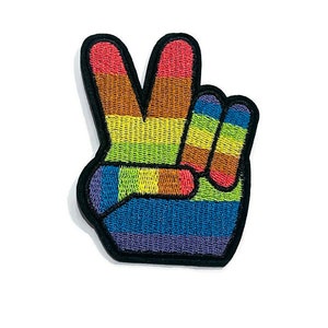 Peut inclure: Patch brodé en forme de signe de paix arc-en-ciel. Le patch est en tissu et a un contour noir. Le signe de paix est composé de bandes de rouge, orange, jaune, vert, bleu et violet.