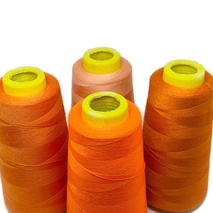 May include: Four spools of thread, two orange and two peach, with yellow plastic tops.
