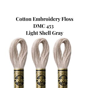 May include: Three spools of DMC 453 Light Shell Gray cotton embroidery floss are displayed against a white background. The text "Cotton Embroidery Floss DMC 453 Light Shell Gray" is above the spools. Each spool is 8 meters (8.7 yards).