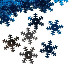 May include: A pile of blue snowflake sequins with a few silver snowflake sequins scattered around them.
