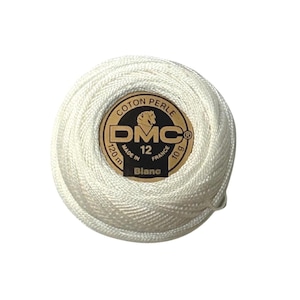 May include: A ball of white DMC Coton Perle thread, size 12, weighing 10 grams and measuring 120 meters. The center label features the DMC logo, the text Coton Perle, Made in France, and the color name Blanc in black and gold lettering.