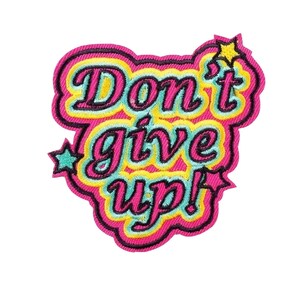 Könnte beinhalten: Ein gestickter Aufnäher in Pink, Gelb und Blau mit dem Text "Don't give up!" in einem Retro-Schriftart-Stil. Der Aufnäher hat auf jeder Seite ein Sternmuster.