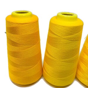 May include: Three spools of bright yellow thread.