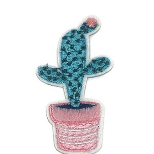 May include: A blue cactus with a pink flower on top, potted in a pink pot with white stripes. The cactus is embroidered on a white background.