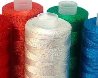 Puede incluir: Cinco carretes de hilo en diferentes colores: rojo, blanco, verde y azul. Los carretes están dispuestos en una fila, con el carrete rojo a la izquierda y el carrete azul a la derecha.