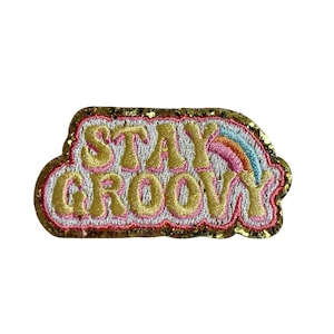 Puede incluir: Parche bordado con las palabras "STAY GROOVY" en hilo dorado. El parche presenta un diseño de arcoíris y un borde dorado con purpurina. Ideal para añadir un toque retro a la ropa o accesorios.