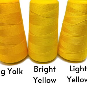 May include: Three spools of thread in different shades of yellow. From left to right, the shades are egg yolk, bright yellow, and light yellow.
