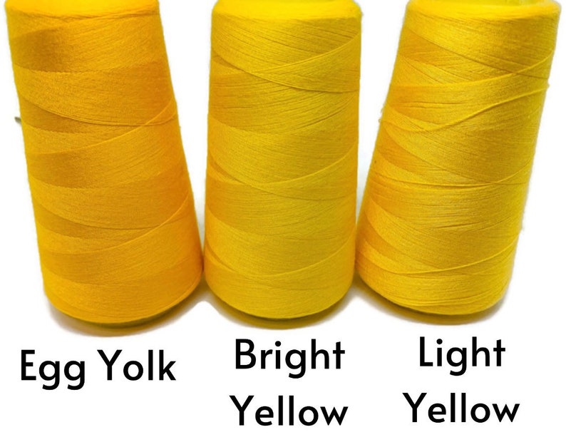 May include: Three spools of thread in different shades of yellow. From left to right, the shades are egg yolk, bright yellow, and light yellow.