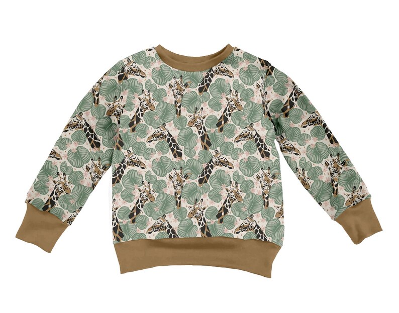 May include: A long-sleeve sweatshirt featuring a repeating pattern of giraffe heads and green tropical leaves on a light background. The garment has a solid brown crew neckline, sleeve cuffs, and a bottom hem, providing a contrast to the print.