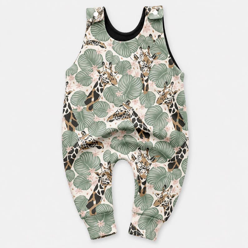 May include: A sleeveless romper featuring a repeating pattern of giraffes and large green tropical leaves on a light background. The garment has a black inner lining and two white snap buttons at the top of the shoulder straps for closure.