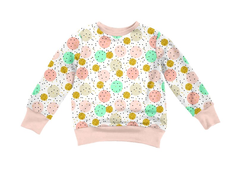 K&ouml;nnte beinhalten: Ein lang&auml;rmeliges Sweatshirt mit wei&szlig;em Hintergrund und einem wiederkehrenden Muster aus hellrosa, mintgr&uuml;nen und goldglitzernden Kreisen. Das Design enth&auml;lt kleine schwarze Sprenkel und ist mit einem einfarbigen hellrosa Rundhalsausschnitt, B&uuml;ndchen und Saum versehen.