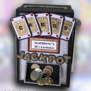 May include: Black card box with a slot for cards. The box has a silver and gold design with the words "CARDS" and "JACKPOT" on it. The box also has a red label that says "Matthew's 30th Birthday".