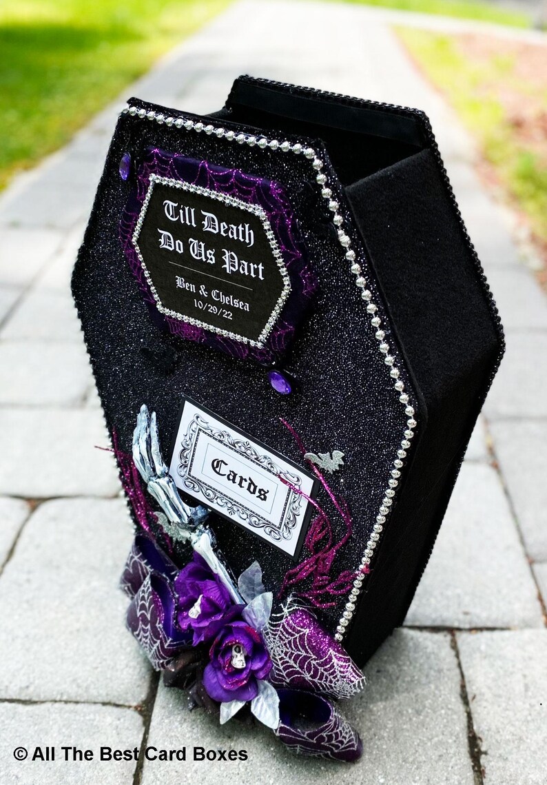 Puede incluir: Una caja de tarjetas negra en forma de ata&uacute;d con un acabado brillante y detalles morados. La caja tiene un letrero que dice "Till Death Do Us Part" con los nombres Ben & Chelsea y la fecha 10/29/22. La caja tambi&eacute;n tiene un letrero que dice "Cards".