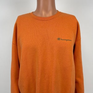 Puede incluir: Sudadera naranja Champion con un pequeño logotipo bordado en la parte delantera.