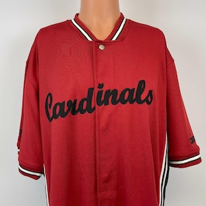 Könnte beinhalten: Rotes Baseballtrikot mit schwarzen und weißen Verzierungen. Das Trikot trägt den Schriftzug "Cardinals" in schwarzer Schrift auf der Vorderseite.