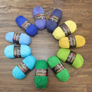 May include: A collection of 10 balls of yarn in various shades of blue, green, and yellow. The yarn is labelled "Scheepjes Colour Crafter".