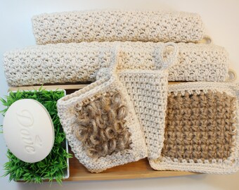 May include: A set of four crocheted bath scrubbies in beige and brown. Two of the scrubbies are made with a beige yarn and two are made with a brown yarn. The scrubbies are arranged on a wooden tray with a bar of soap and a small potted plant.